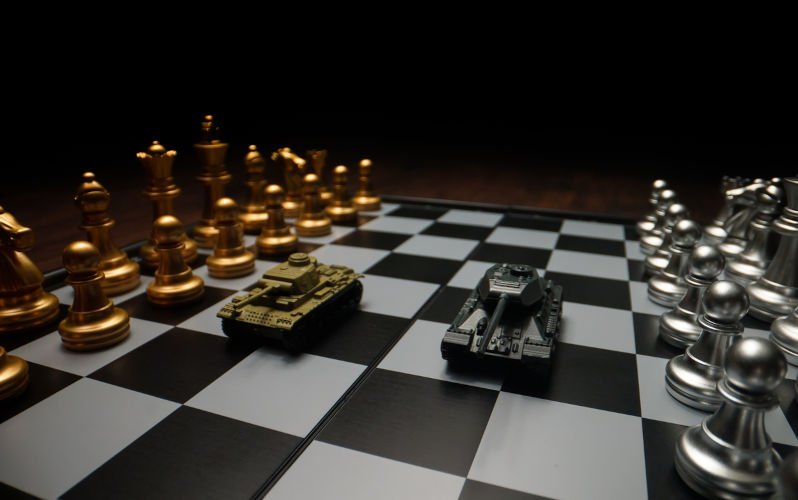 Toy-tanks-with-chess-on-chessboard.-Concept-of-military-strategy.-